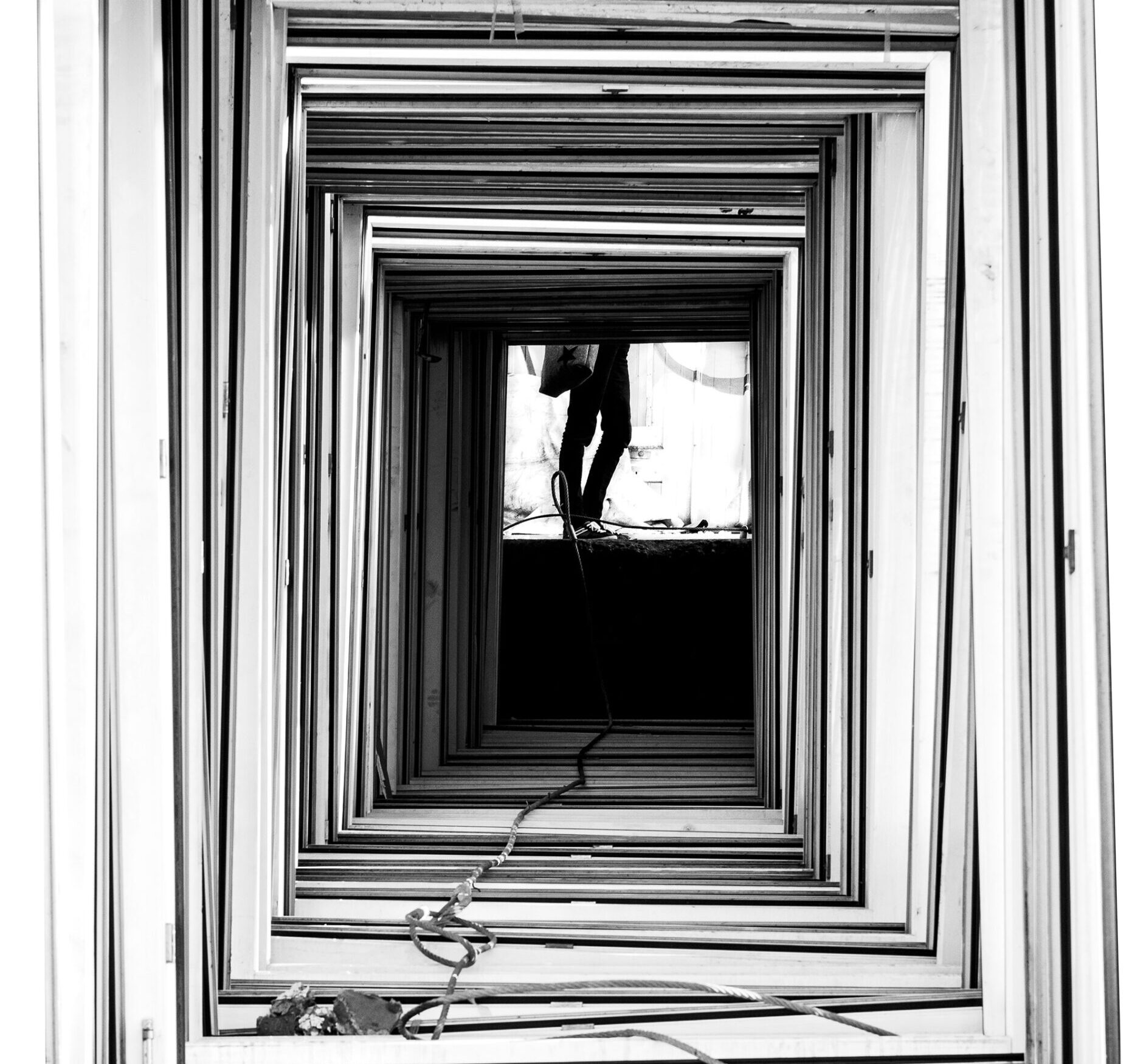 Semi-abstract image of a person's legs at the end of a stack of frames