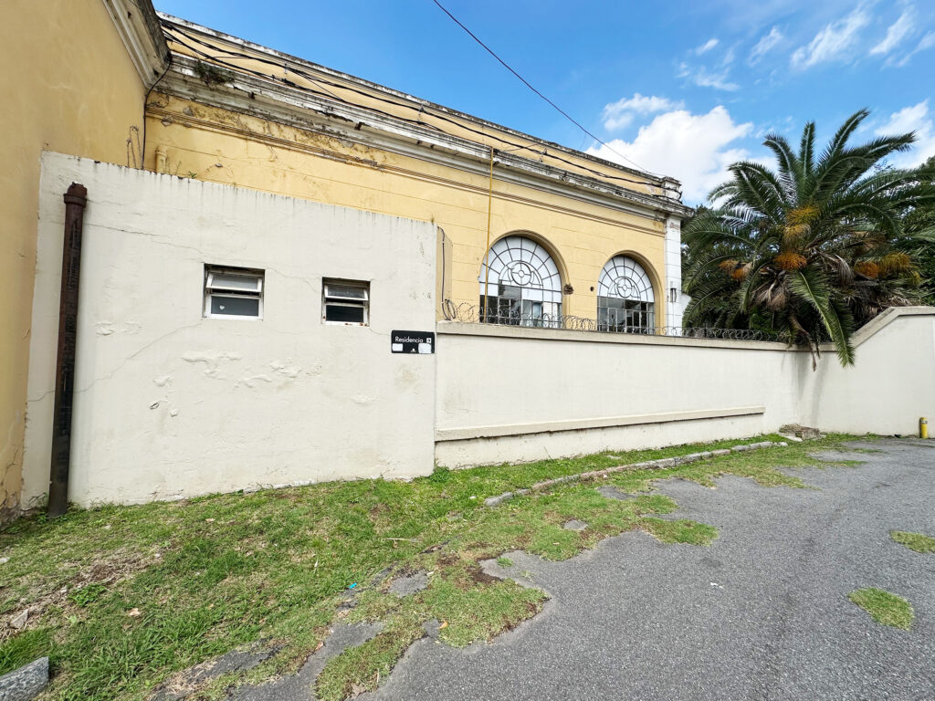 Walkway to residency offices, yellow building beyond a wall