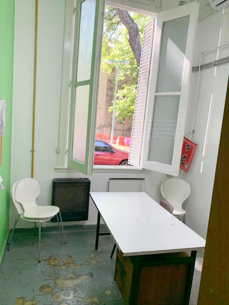 a consultation office, with green walls, a large window, and a desk with two chairs