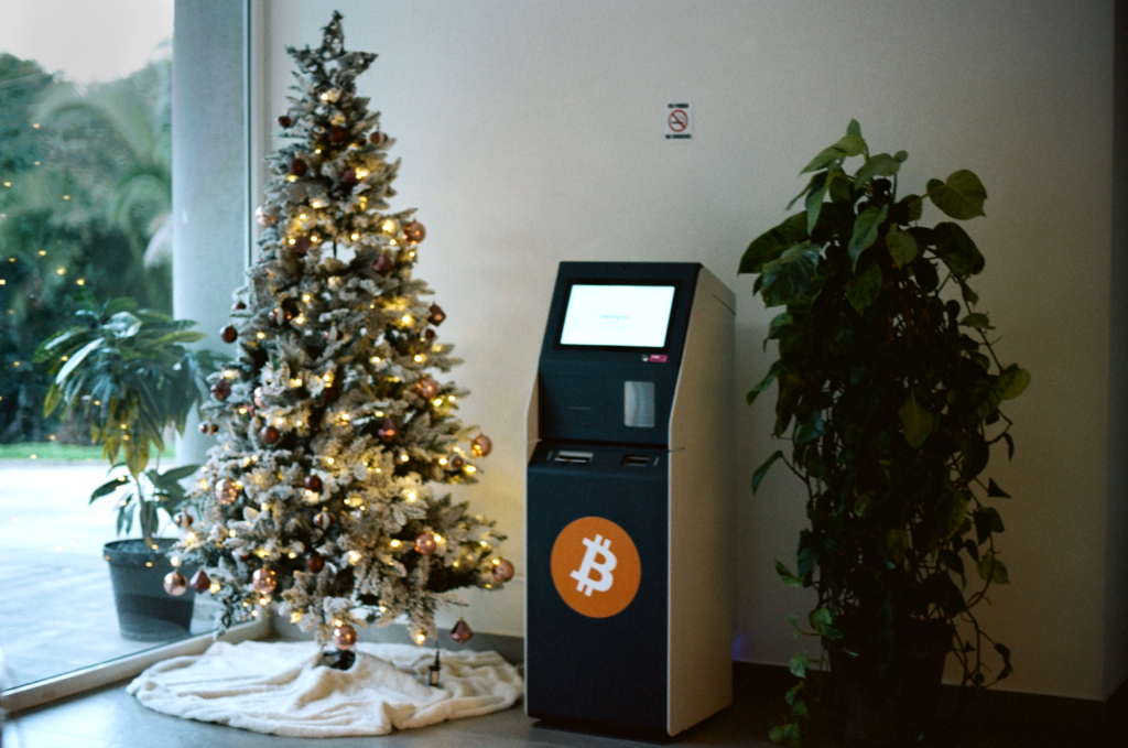 a cash-machine next to a Christmas tree and house plant