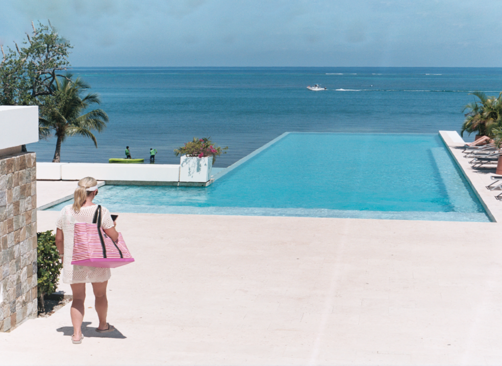 woman walking toward a swimming pool, with sea as backdrop