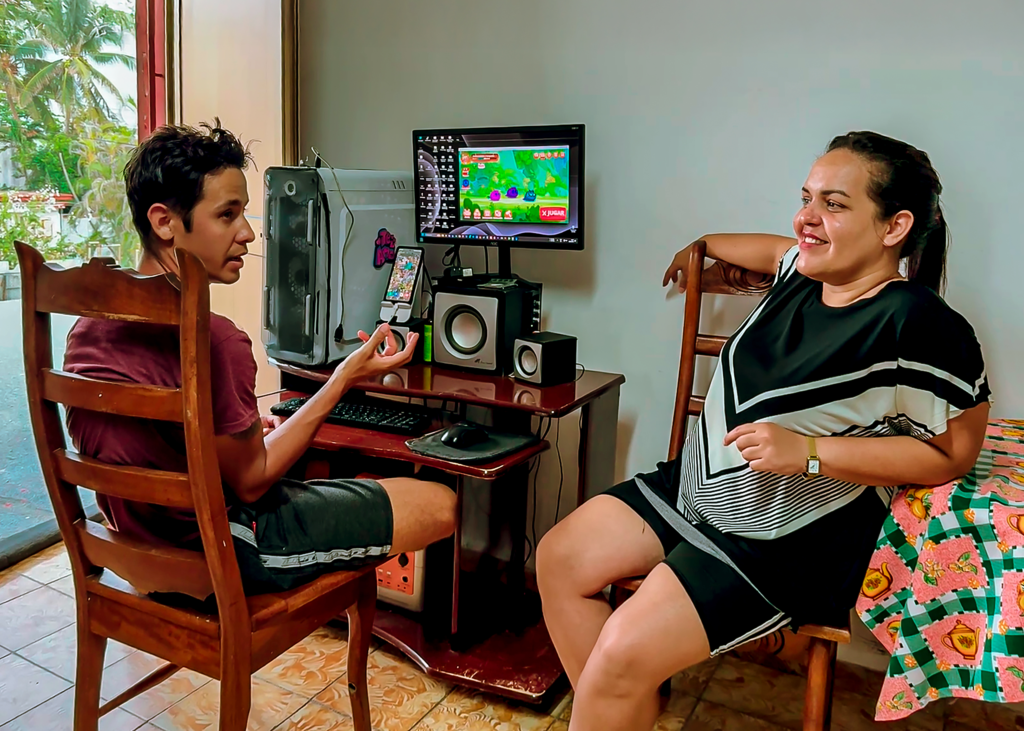 man and woman talking at computer desk