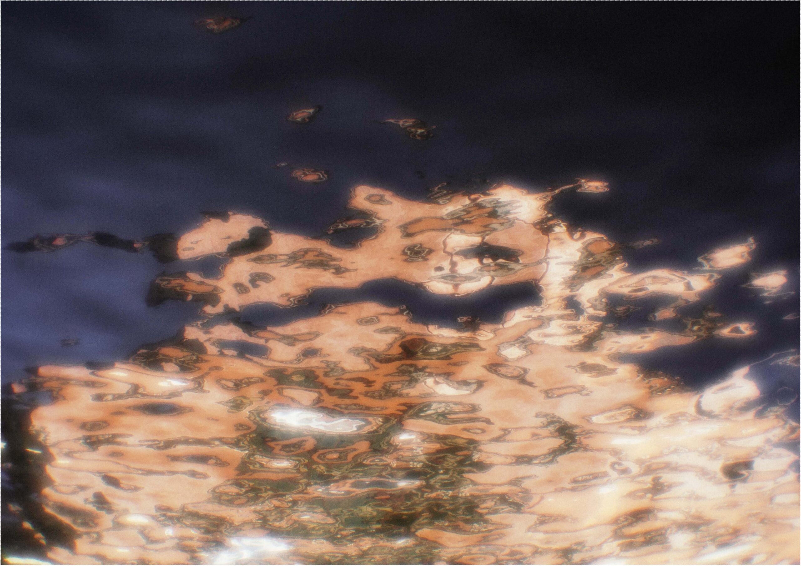 Close-up photo of golden light reflected on the surface of water.
