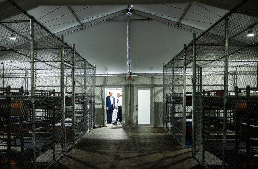 Interior shot of detention center showing bunk beds inside chain-link cages
