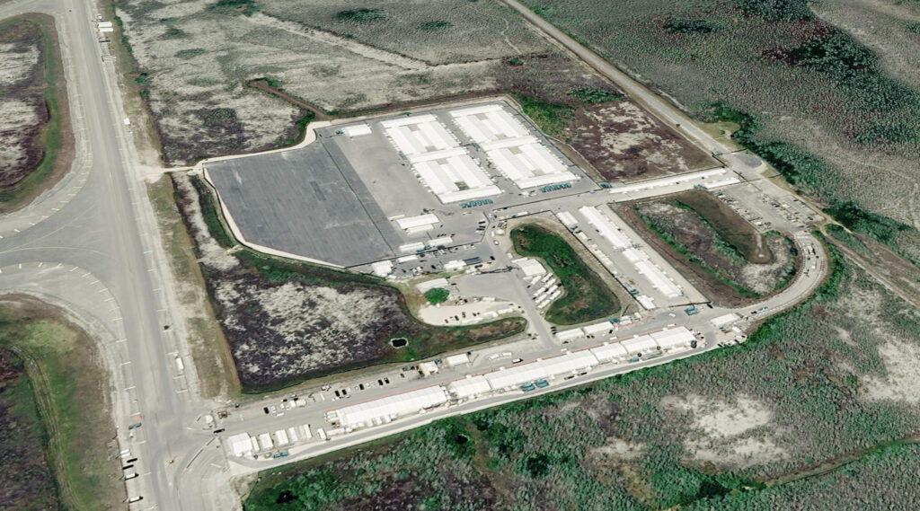Aerial photograph of Everglades detention center, featuring tents, buildings, and vehicles on the space of the old airstrip.