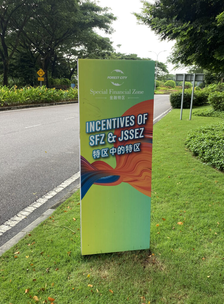 Green sign advertising the Forest City Special Economic Zone alongside a street